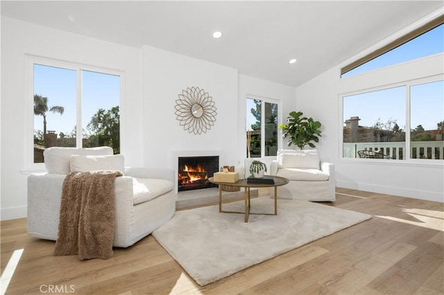 living room with a wealth of natural light, lofted ceiling, and light wood-type flooring