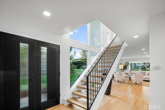 stairs with french doors and hardwood / wood-style flooring