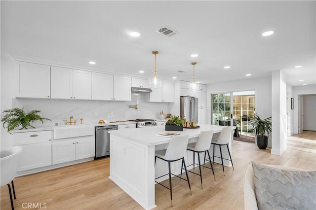 kitchen with light wood-type flooring, stainless steel appliances, white cabinetry, and sink