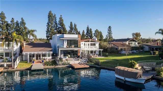 back of house with a yard, a water view, and a balcony