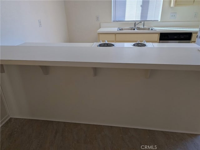 kitchen with a breakfast bar area, dishwasher, dark wood-type flooring, and sink