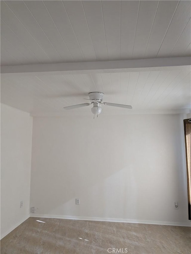 unfurnished room featuring beamed ceiling, ceiling fan, and concrete floors