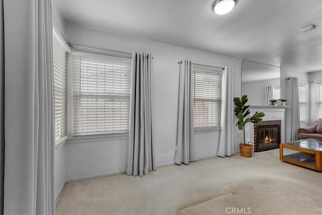 interior space with a brick fireplace and light colored carpet