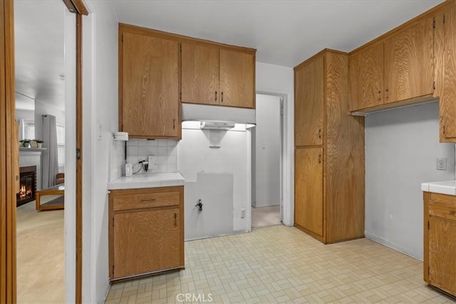 kitchen with tile countertops, tasteful backsplash, a fireplace, and brown cabinets