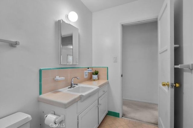 half bathroom with toilet, decorative backsplash, and vanity