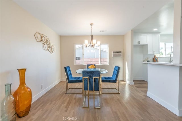 dining space featuring light wood-type flooring, a notable chandelier, and a wall unit AC