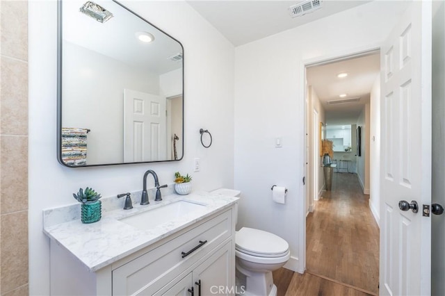 bathroom featuring toilet, vanity, and hardwood / wood-style flooring