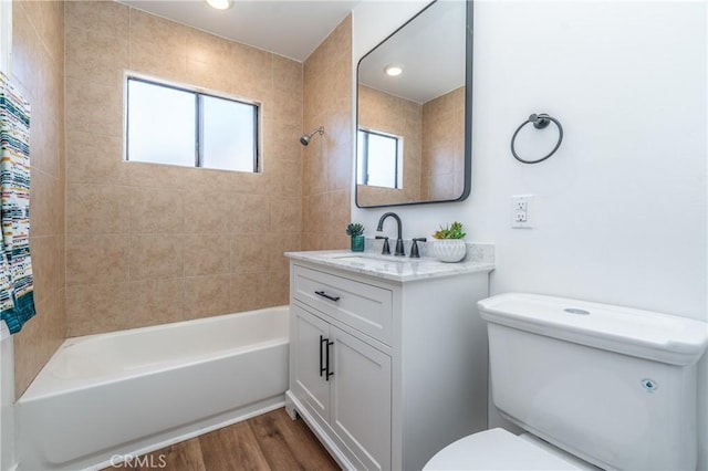 full bathroom featuring toilet, tiled shower / bath combo, hardwood / wood-style flooring, and vanity