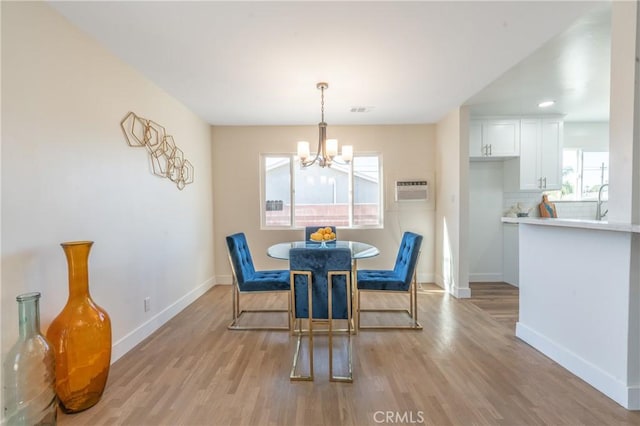 dining room with a wall mounted AC, light wood-type flooring, and an inviting chandelier