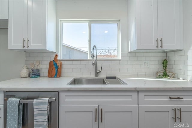 kitchen featuring white cabinetry, backsplash, dishwasher, light stone countertops, and sink