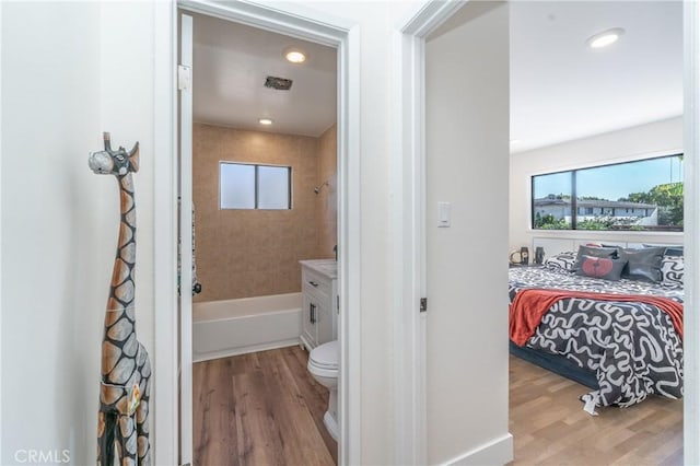 full bathroom with toilet, vanity, tiled shower / bath combo, and hardwood / wood-style floors