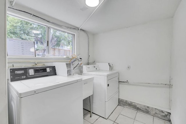 clothes washing area with light tile patterned floors and washer and dryer