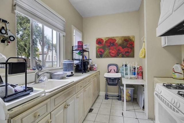 kitchen featuring sink, white range with gas cooktop, custom exhaust hood, and light tile patterned flooring