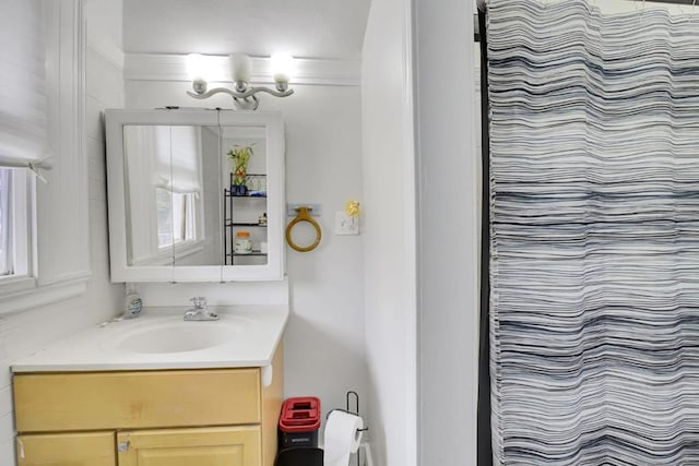 bathroom featuring walk in shower, vanity, and crown molding