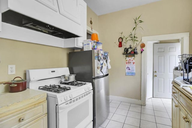 kitchen with white range with gas stovetop, cream cabinetry, and light tile patterned flooring