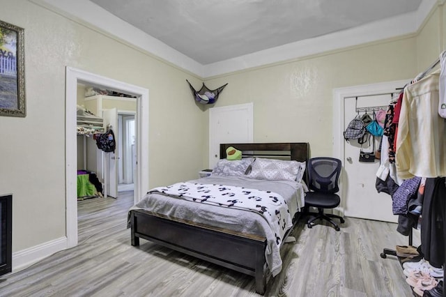 bedroom with a closet, crown molding, and light hardwood / wood-style flooring