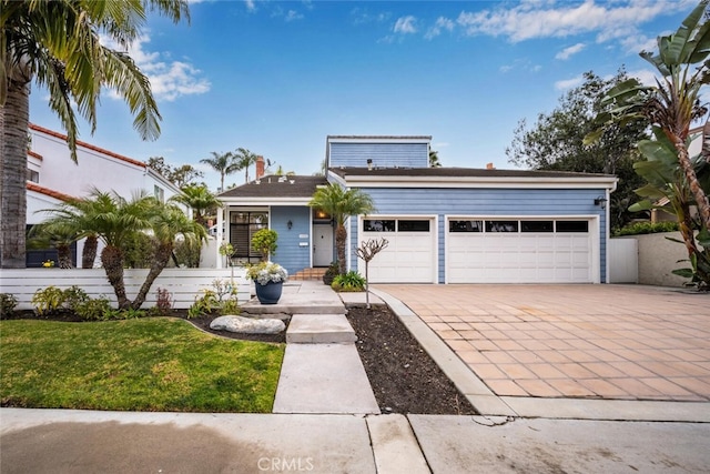 view of front facade featuring decorative driveway, a garage, and a front yard