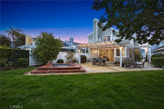 back house at dusk with a lawn, a pergola, and a patio