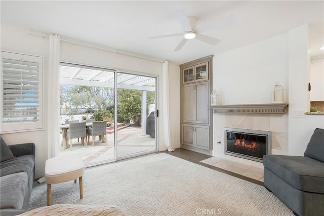 living room with a tile fireplace, ceiling fan, and wood-type flooring