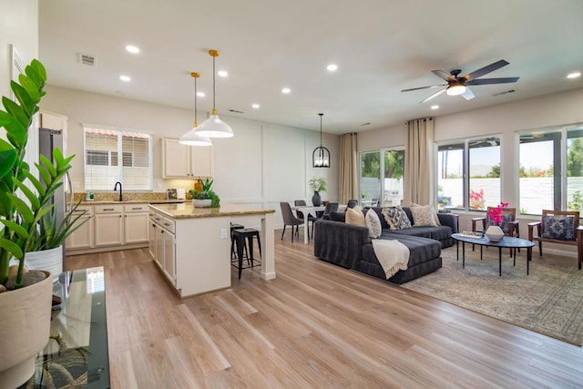 living room featuring ceiling fan, sink, and light hardwood / wood-style floors