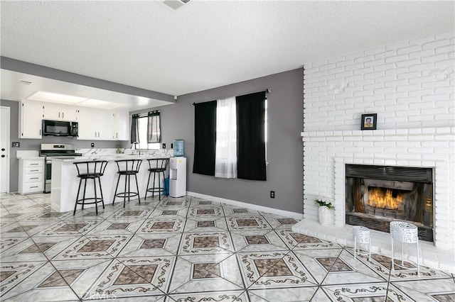 kitchen with stainless steel range, a brick fireplace, kitchen peninsula, a breakfast bar area, and white cabinets