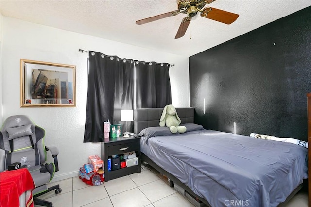 bedroom featuring ceiling fan, light tile patterned floors, and a textured ceiling