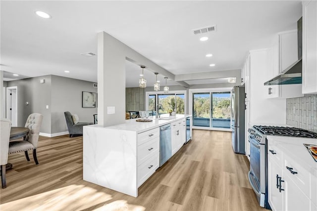 kitchen featuring appliances with stainless steel finishes, wall chimney exhaust hood, backsplash, and white cabinetry