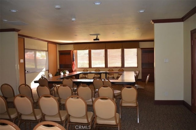 dining room with a wealth of natural light, crown molding, and dark carpet