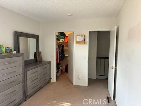 carpeted bedroom with a spacious closet, a closet, and a textured ceiling