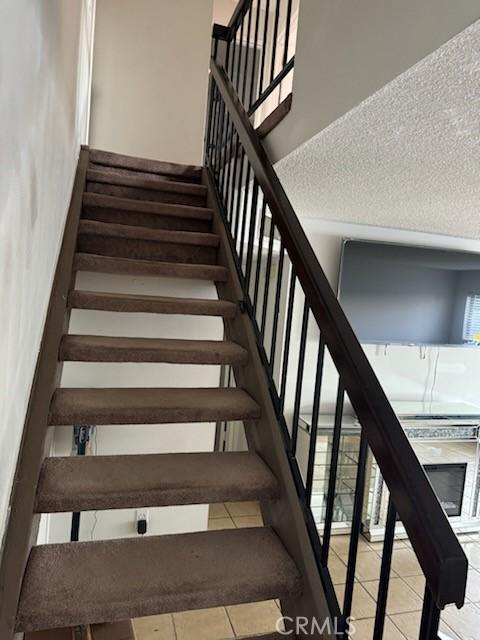 stairs featuring tile patterned flooring and a textured ceiling