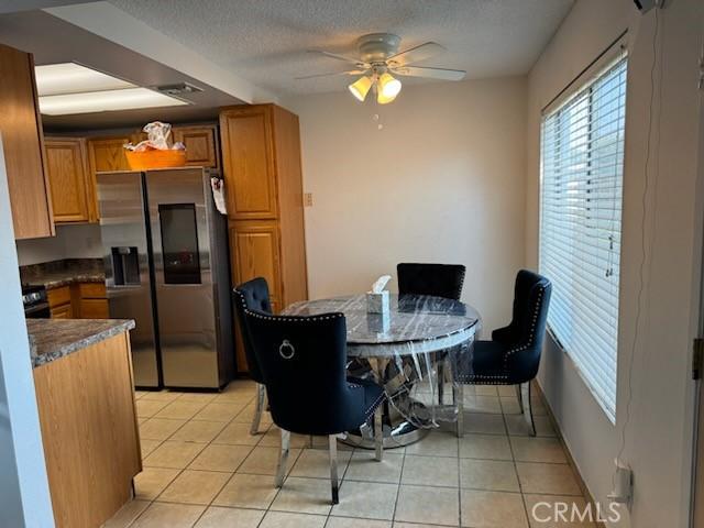 kitchen with stainless steel fridge, light tile patterned floors, a textured ceiling, and ceiling fan