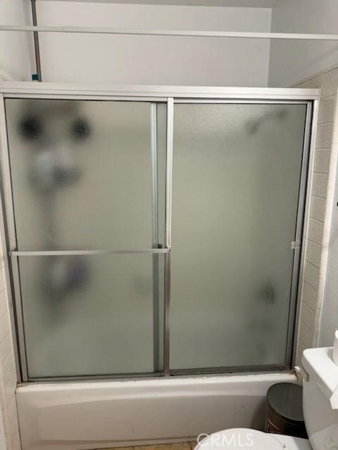 bathroom with toilet and combined bath / shower with glass door