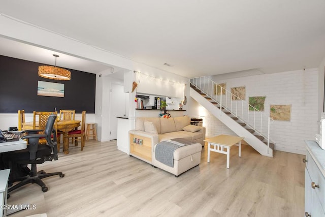 living room with light wood-type flooring and brick wall