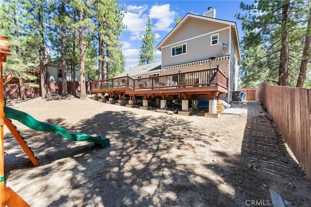 rear view of property with a playground and a wooden deck