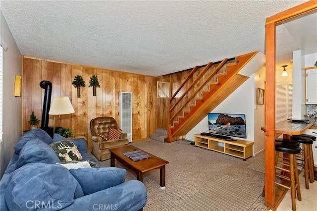 living room featuring carpet flooring, wood walls, and a textured ceiling