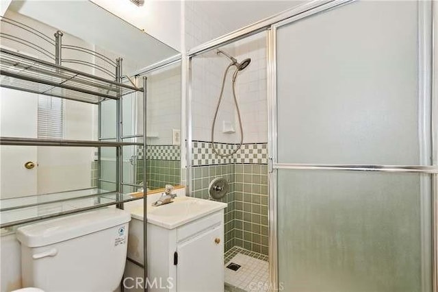 bathroom with a shower with door, vanity, and toilet