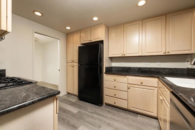 kitchen featuring sink, light hardwood / wood-style flooring, dishwasher, black refrigerator, and dark stone countertops