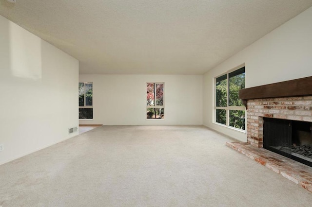 unfurnished living room with light carpet, a brick fireplace, and a textured ceiling