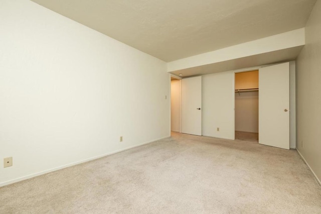 unfurnished bedroom featuring light colored carpet, a closet, and a walk in closet