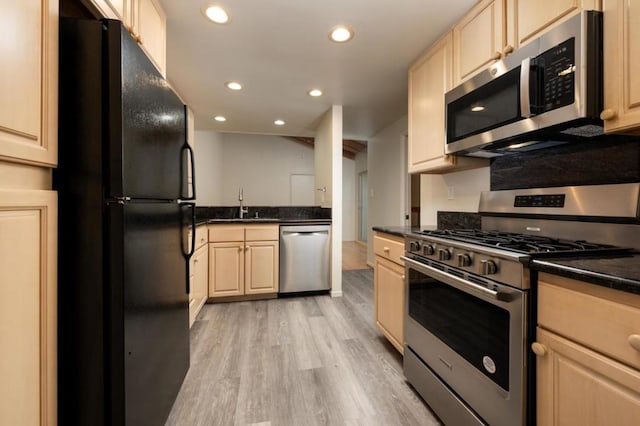 kitchen with stainless steel appliances, sink, and light hardwood / wood-style flooring