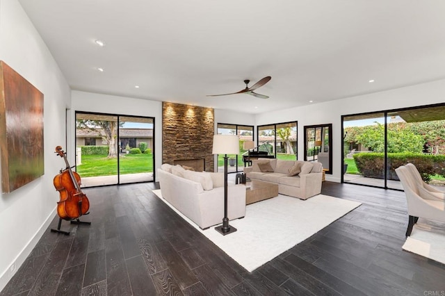 unfurnished living room with plenty of natural light, dark wood-type flooring, and a stone fireplace