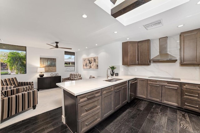 kitchen with visible vents, a peninsula, a sink, wall chimney range hood, and black electric cooktop