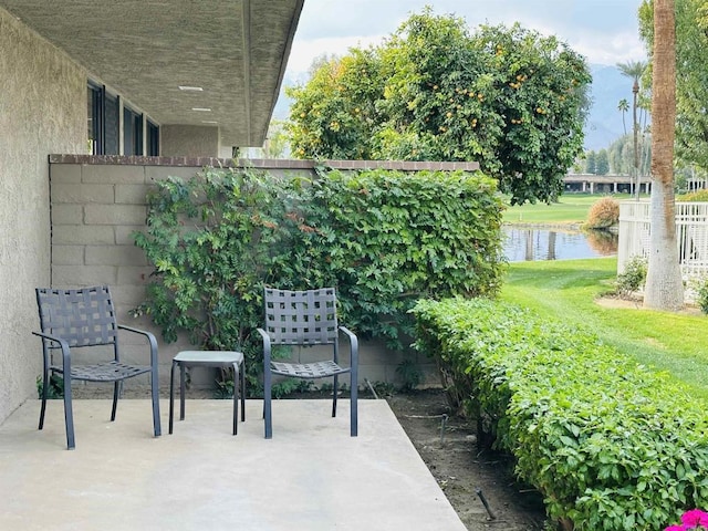 view of patio / terrace featuring fence and a water view