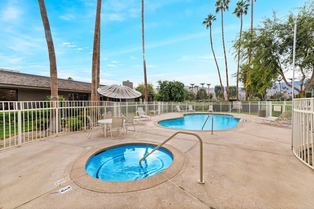 pool with fence, a community hot tub, and a patio area