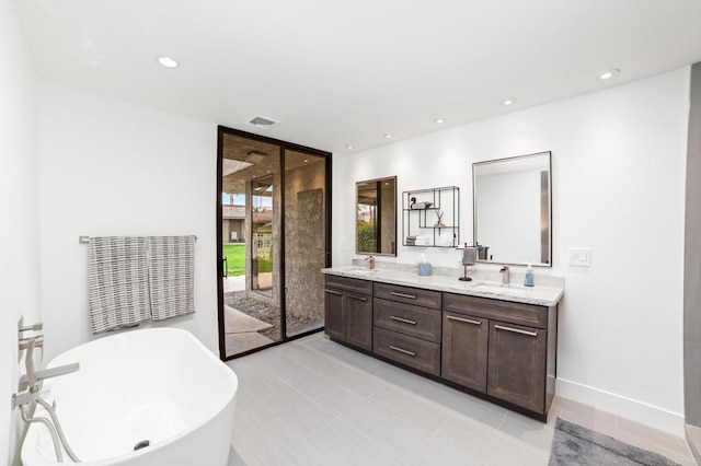 bathroom with double vanity, expansive windows, recessed lighting, a freestanding tub, and a sink