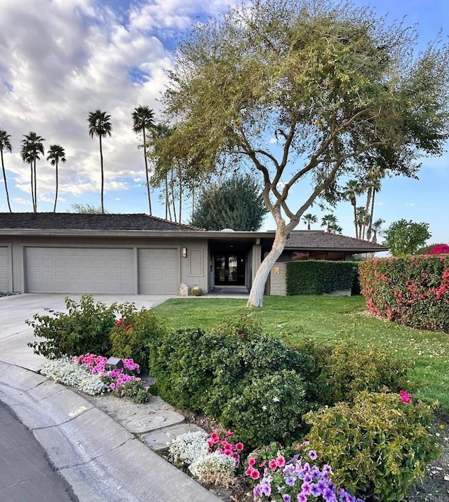 ranch-style house featuring a garage, concrete driveway, and a front lawn