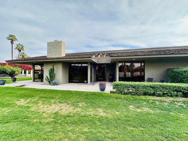 rear view of house featuring a yard, a patio area, and stucco siding