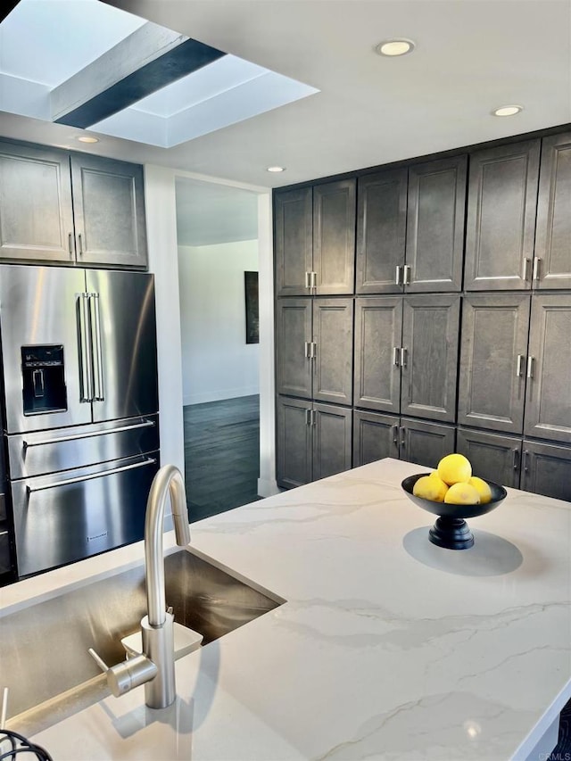 kitchen featuring wood finished floors, light stone counters, recessed lighting, and high end fridge