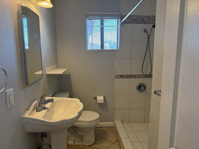 bathroom with tiled shower, tile patterned flooring, and toilet