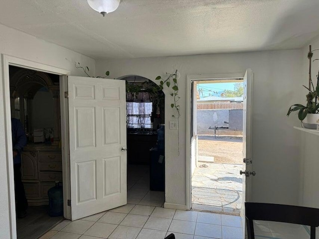 doorway featuring light tile patterned floors and a textured ceiling